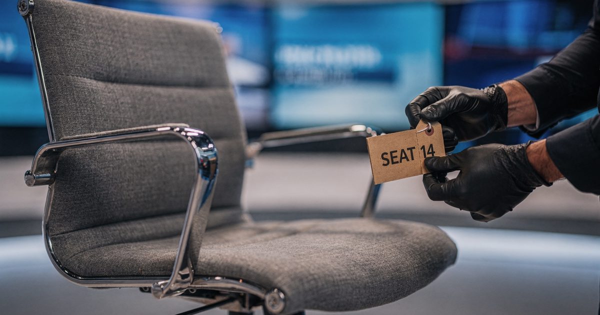 Tight close detail under cool early-morning studio lighting of an empty grey swivel anchor chair on a business news set, a stagehand's gloved hands looping a.