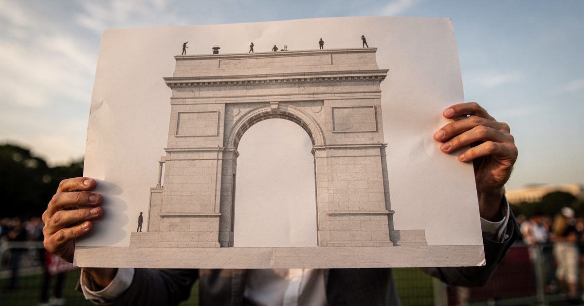Low-angle late afternoon shot on the National Mall of two people cropped at the waist holding up a large foam-board architectural rendering of a stone arch.