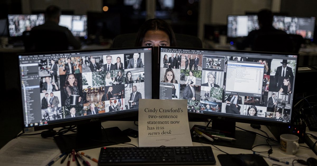Mid-shot across an open-plan entertainment newsroom near midnight lit only by monitor glow, a photo editor visible just as a forehead and eyes in the gap.