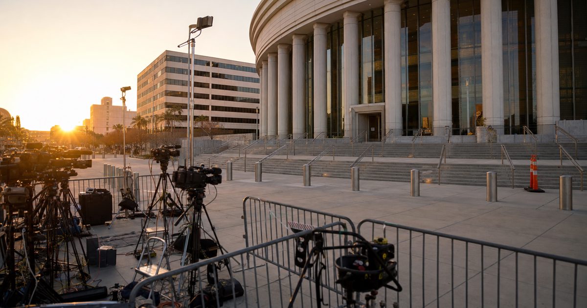 Wide news photograph outside a Las Vegas courthouse at sunrise, television crews setting up cameras behind barriers, empty entrance in view, no recognizable.