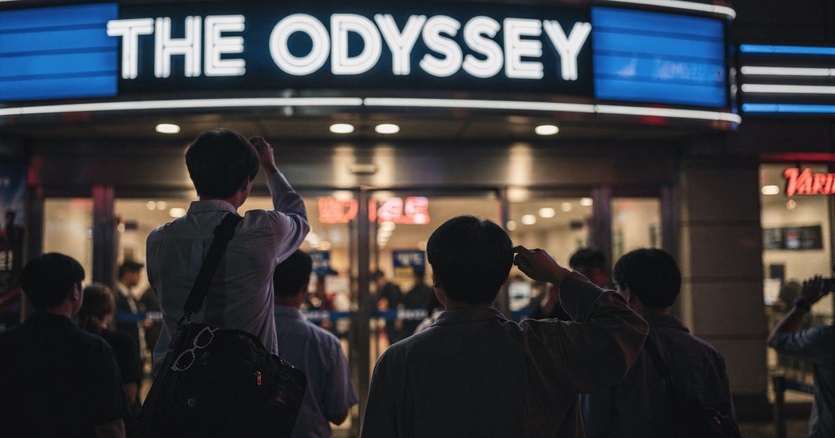 Night neon on a Seoul multiplex facade as patrons cropped at the shoulders pass under a marquee reading "THE ODYSSEY", a pair of unused 3D glasses hooked on.