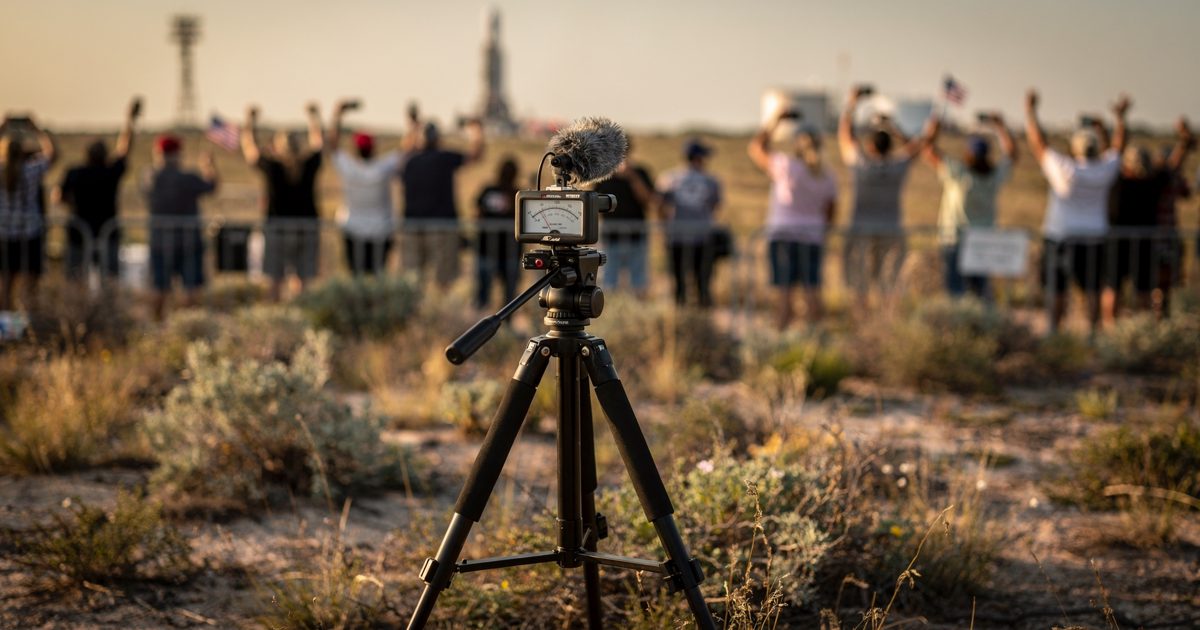 Close shot in warm early morning light on scrub grassland near a South Texas launch site of a handheld sound level meter clamped to a photographer's tripod.