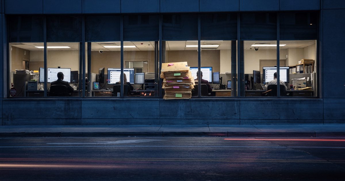 Wide shot at blue dusk from across a Washington street looking into the lit upper floor of a federal office building, a row of investigators seen small through.