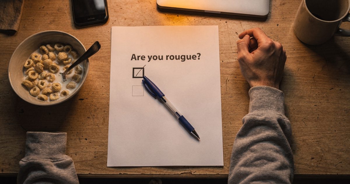 Overhead shot straight down onto a kitchen table in the first orange light through a window, two forearms in a grey hoodie resting either side of a printed.