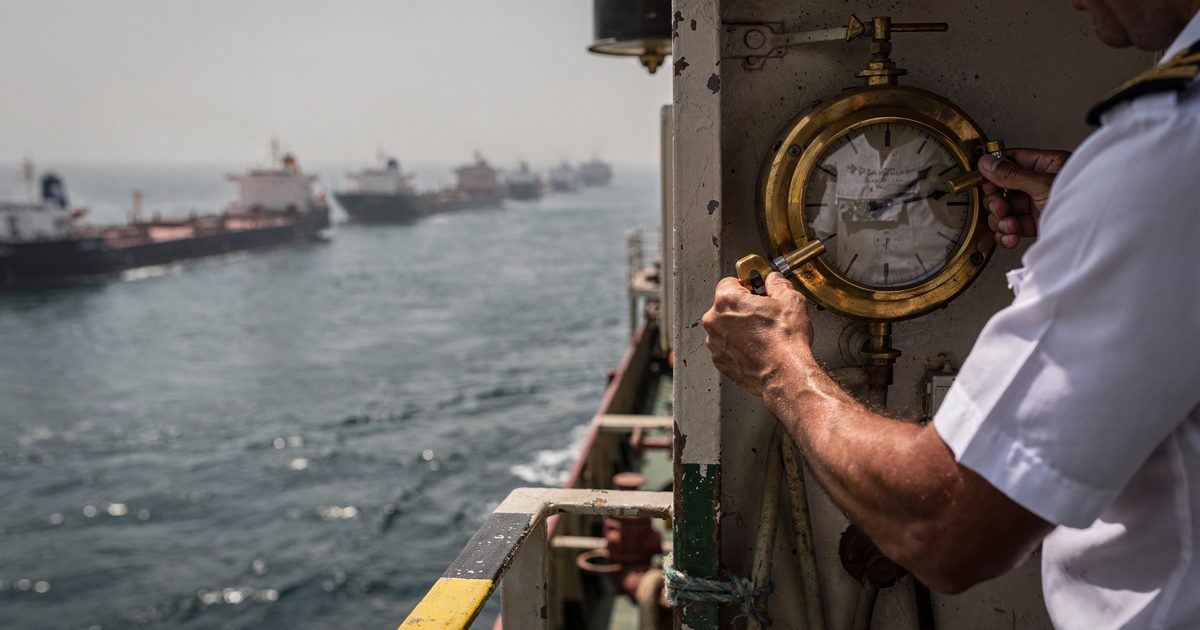 Close detail in hard midday Gulf sun on the bridge wing of a crude tanker riding at anchor, an officer's hands cropped at the cuffs winding a brass ship's.